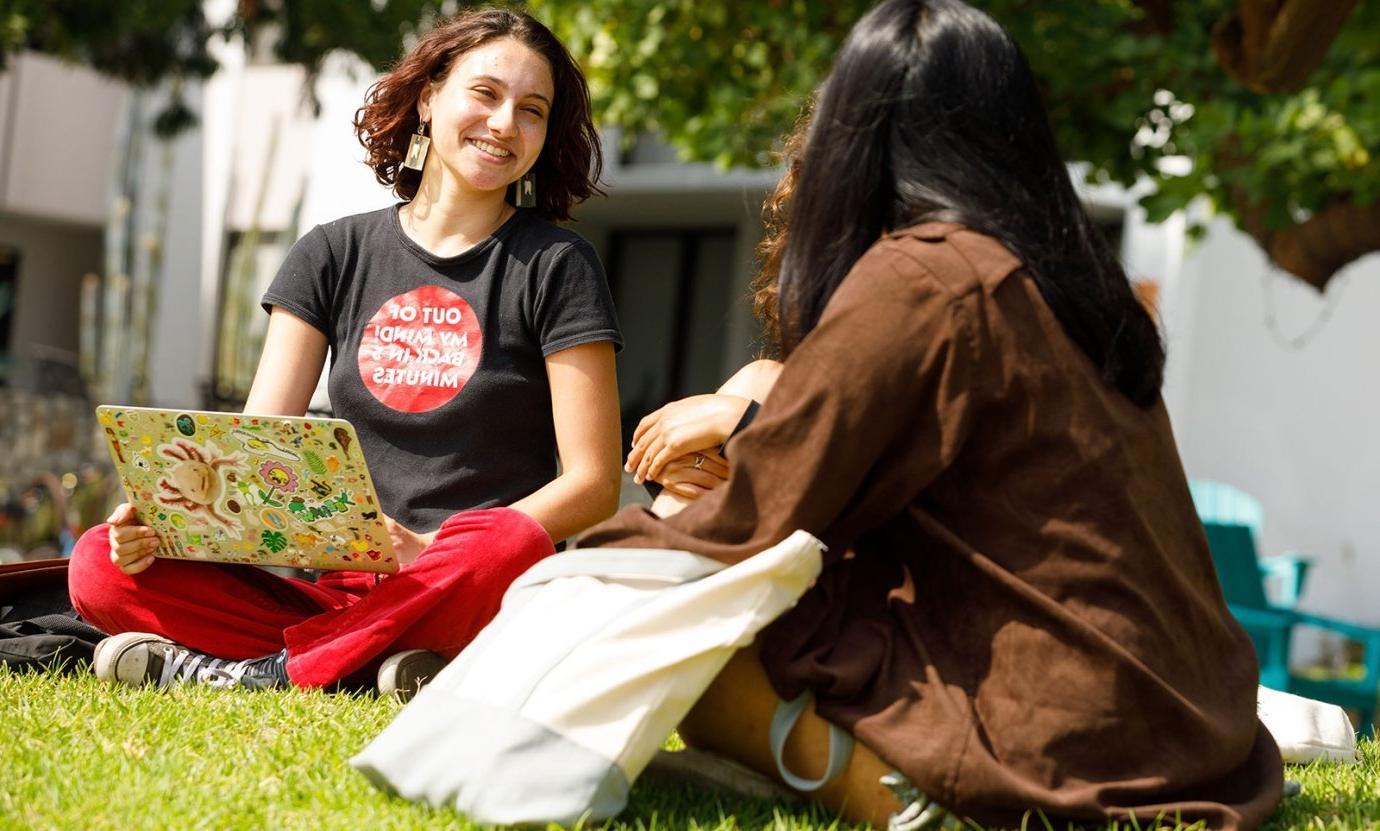 two students sit and talk on the mounds